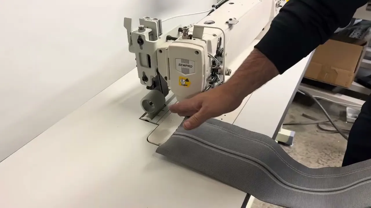 A long arm SEWPRO walking foot machine sewing grey canvas